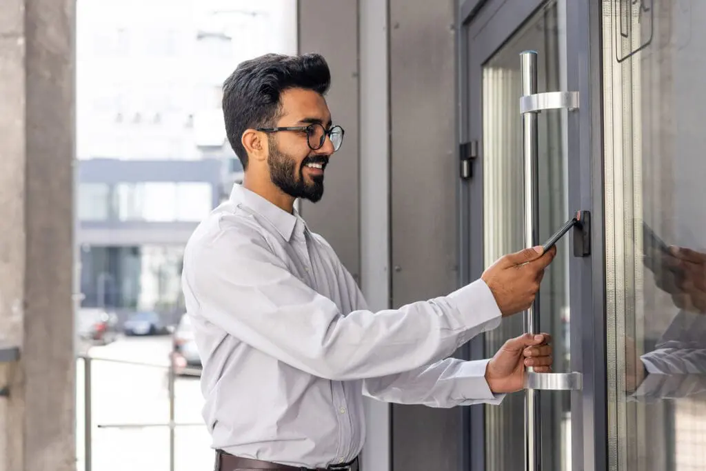 Young business man using his smartphone to open a commercial access control door lock