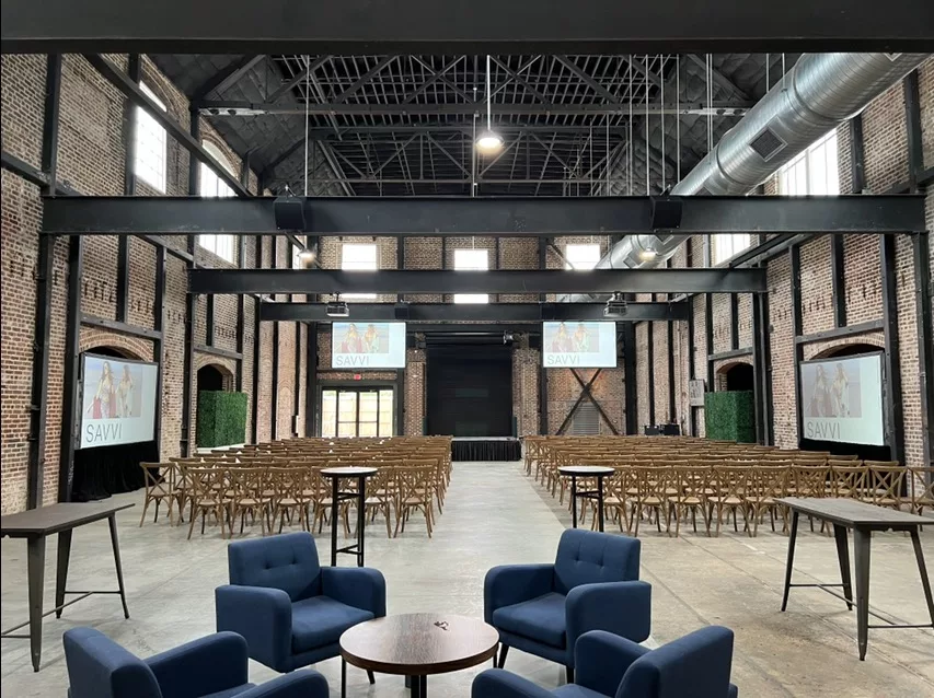 Image showing mcc's av rentals setup in a modern building with two av projector screens at the far end of the room and one screen on each side of the room.