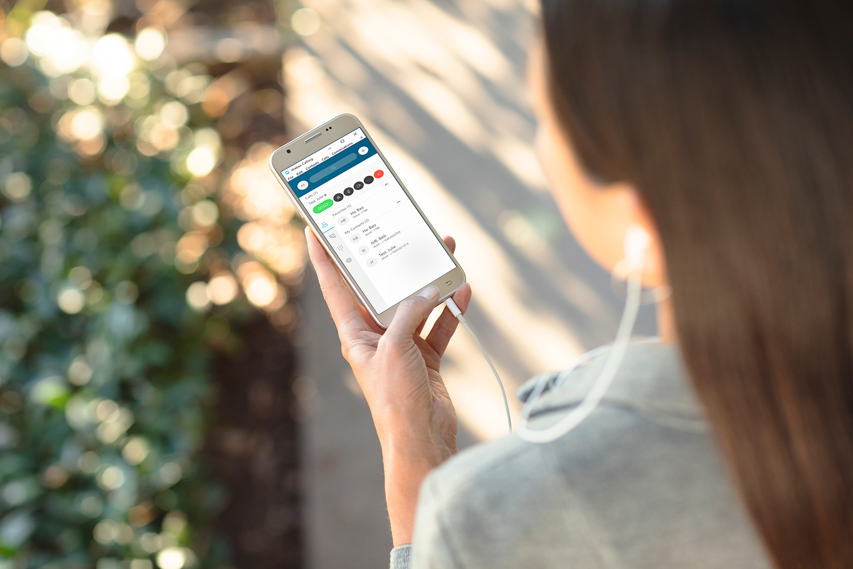 Woman holding a cellphone showing webex meetings