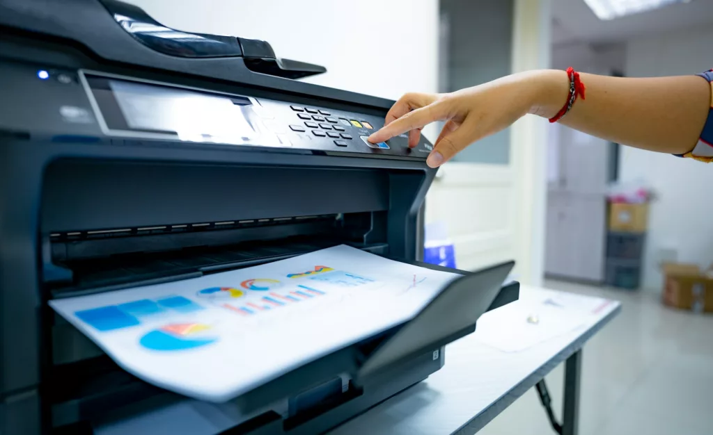 Office worker prints paper on multifunction laser printer. Copy, print, scan, and fax machine. Image for e-faxing/digital fax pages of the document solutions section of the mcc website