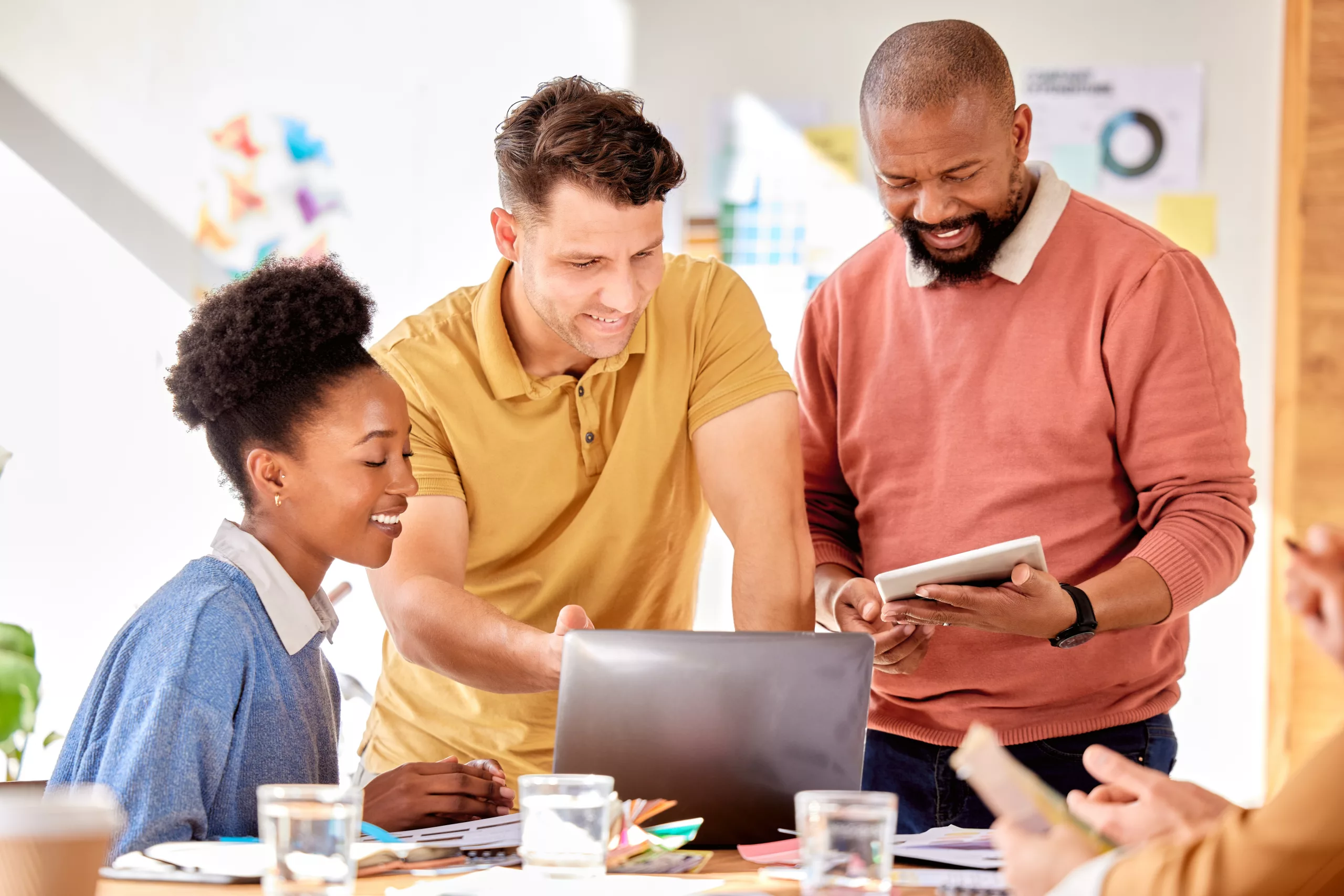 Three professional business individuals engaging in a productive discussion over a computer, exploring the practical benefits and efficiency of using a document management software. This scene exemplifies the transformative power of document management systems and workflow automation in the modern business environment.