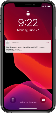 Apple iPhone lock screen with a notification from MCC's business security systems about a business closing late.